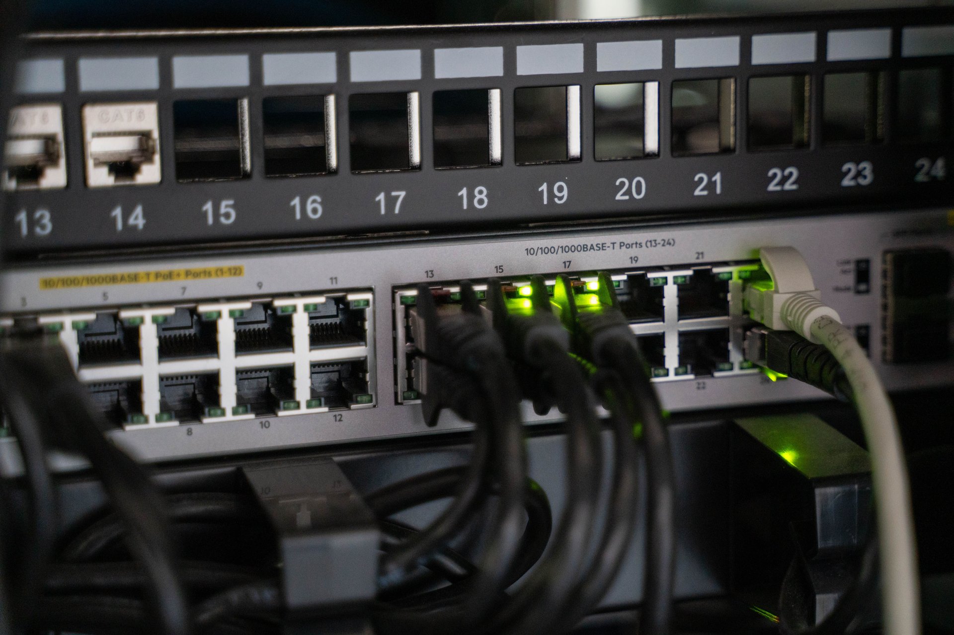 Patch panel con cables Ethernet conectados a switch PoE+ empresarial en rack de red