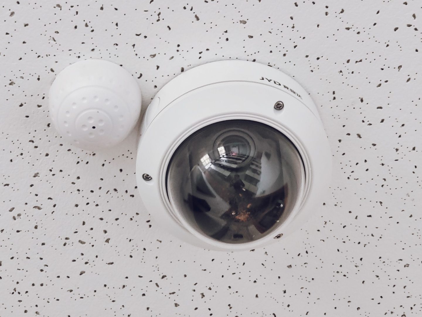 ES: Cámara domo CCTV instalada en techo de tienda retail, ángulo cenital sobre zona de cajas