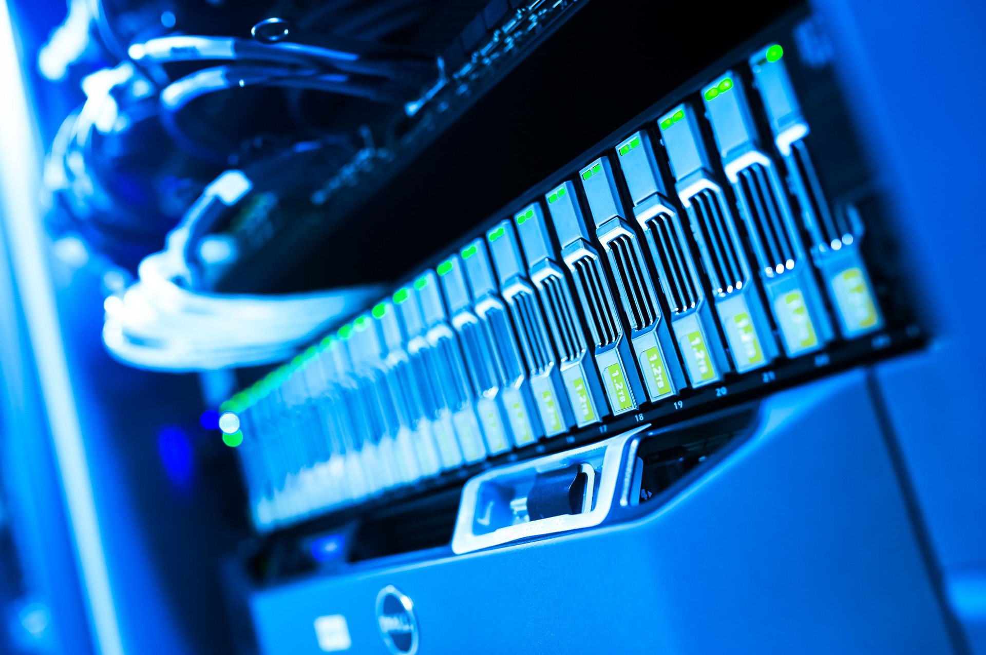 Centro de datos corporativo con hileras de servidores iluminados por LEDs azules — la infraestructura física donde corren los modelos de AI cuyos agentes pueden ensamblar capacidades de vigilancia a partir de fragmentos de código aparentemente benignos