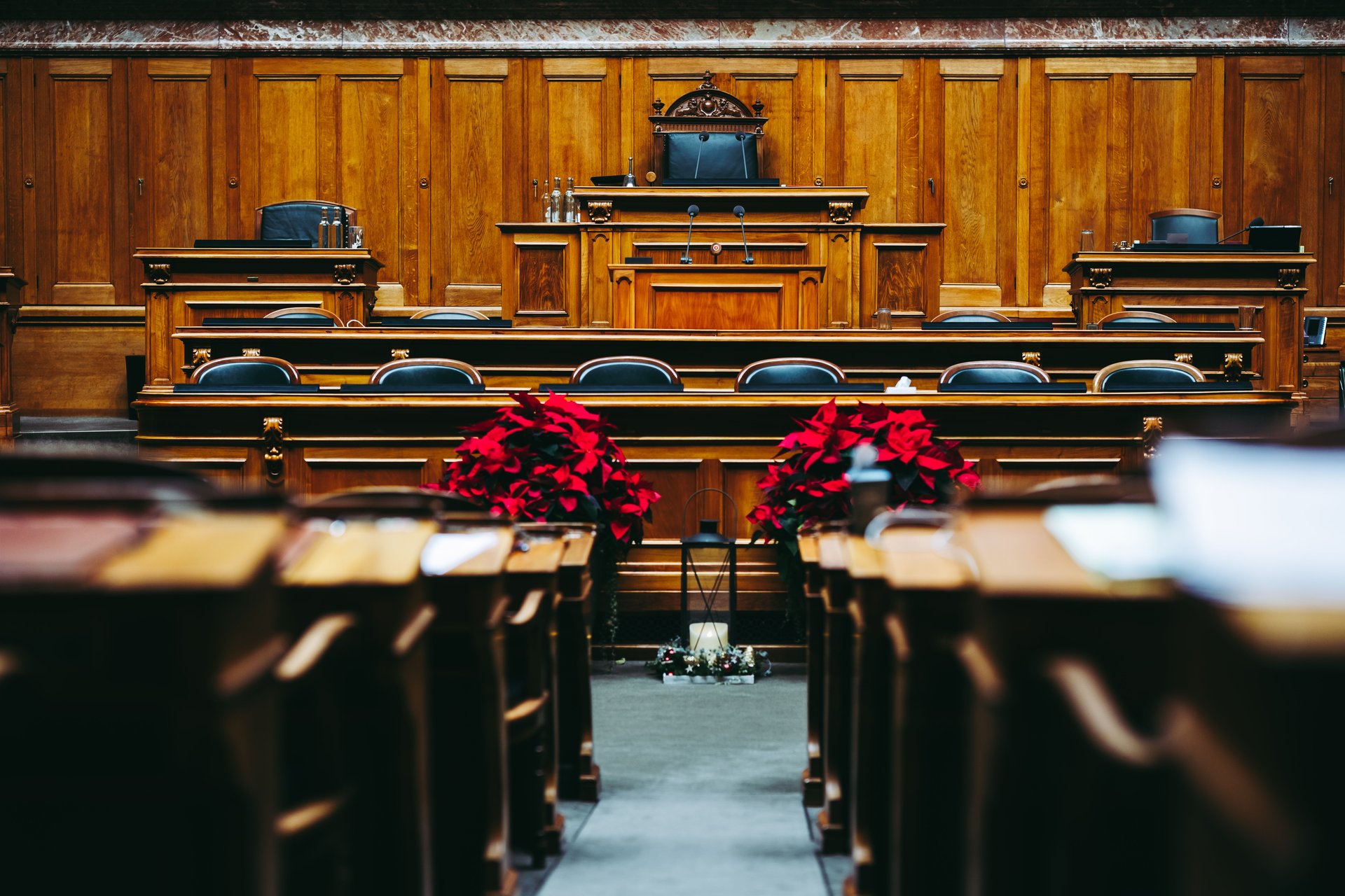 Sala de tribunal vacía con sillas de cuero, escritorios de madera y micrófonos — arquitectura institucional donde una resolución de cobertura quedó sin firmar