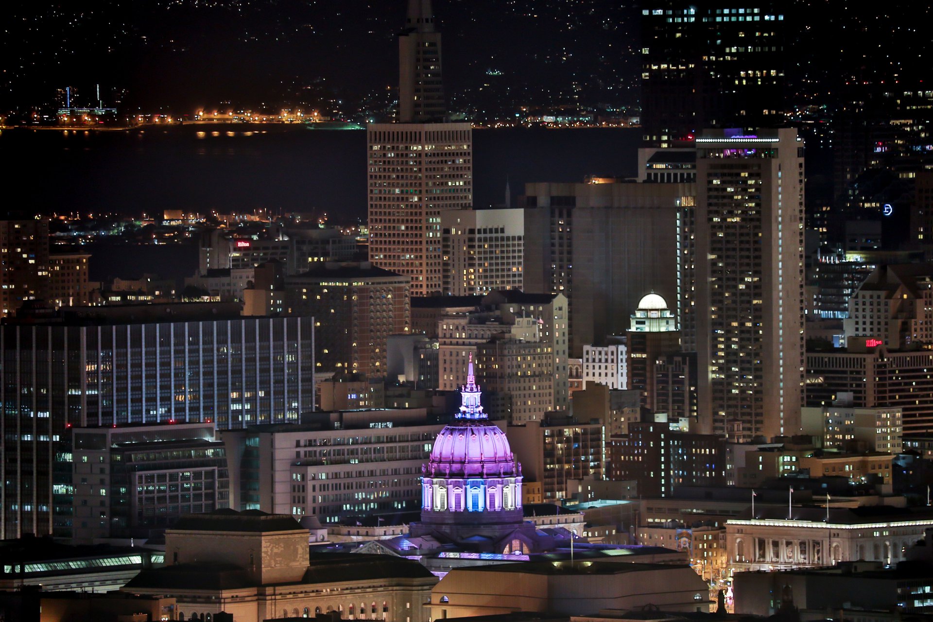 Cúpula del ayuntamiento de San Francisco iluminada en violeta contra el skyline nocturno — arquitectura cívica enmarcando la crítica estructural de EFF a la política ALPR de la ciudad