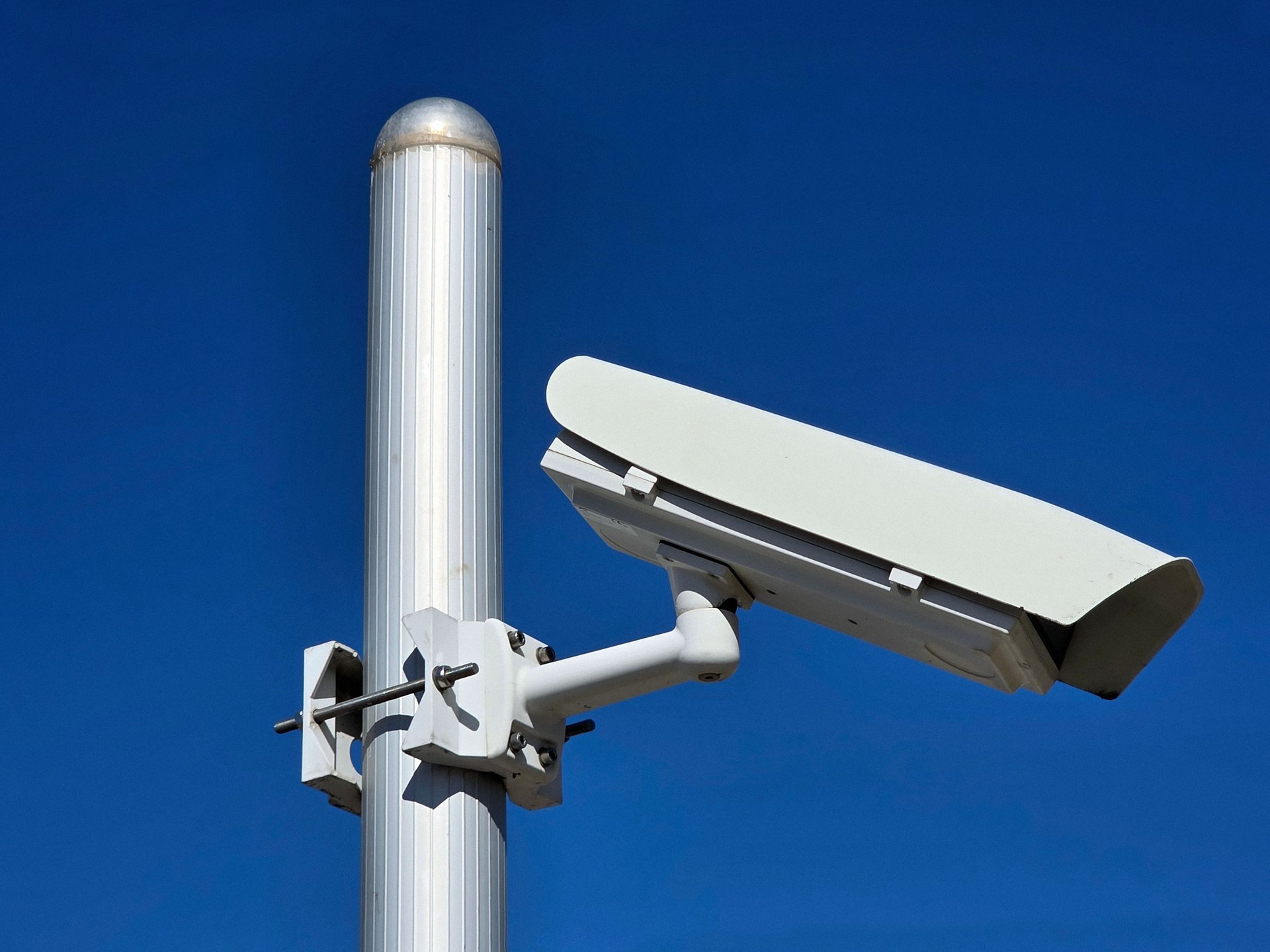 Cámara de vigilancia urbana sobre un poste de aluminio contra el cielo azul