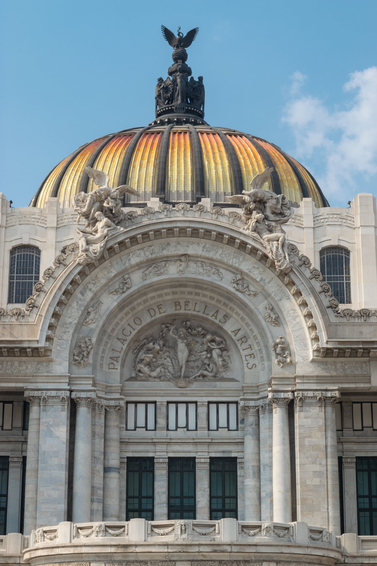 Fachada neoclásica del Palacio de Bellas Artes en Ciudad de México con cúpula dorada y columnas de mármol