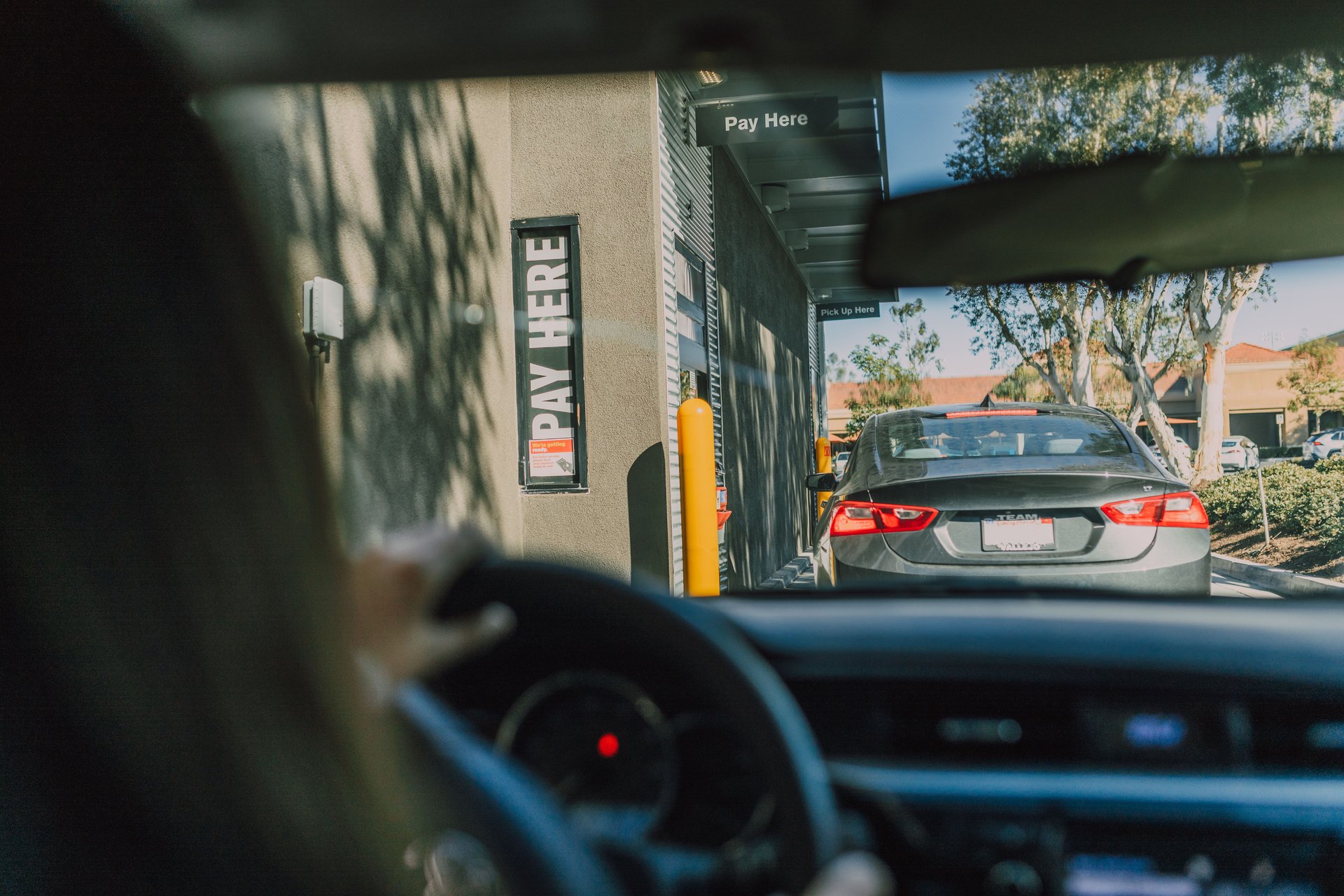 Cola de autos en drive-thru de restaurante de comida rápida vista desde el parabrisas